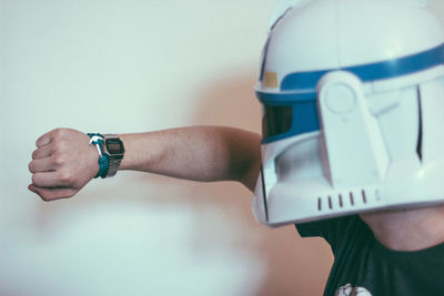 Close-up of man wearing mask while checking time by wall