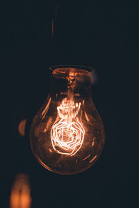 Close-up of illuminated light bulb against black background