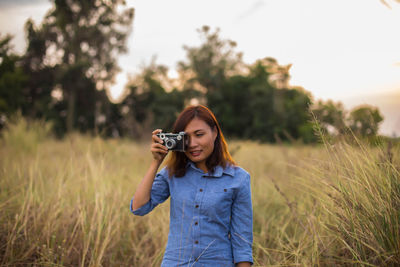 Young woman photographing on field