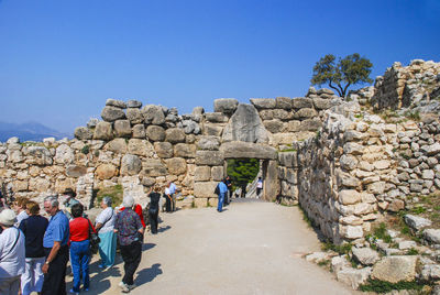 People on rock against blue sky