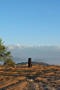 Man standing on mountain against clear blue sky