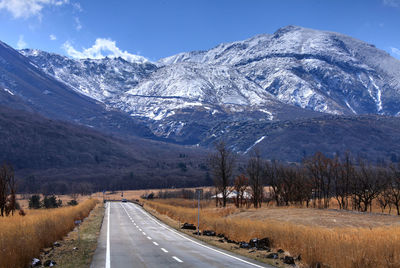 Road by snowcapped mountains against sky