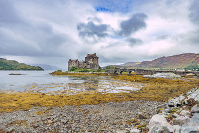 Old building by water against sky