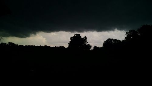 Silhouette of trees against cloudy sky