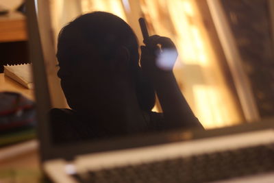 Reflection of woman on laptop screen