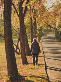 Full length of woman walking on footpath amidst trees