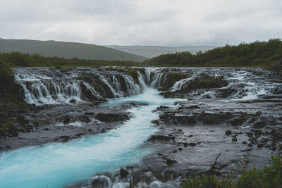 Scenic view of waterfall against sky