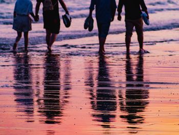 Low section of people walking on beach