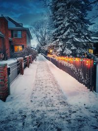 Snow covered walkway amidst buildings in city