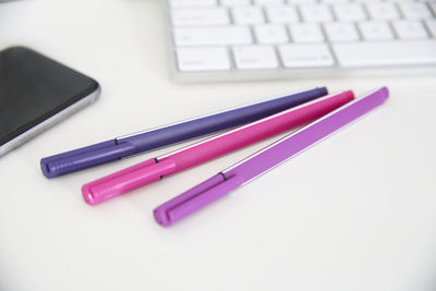 High angle view of pens with computer keyboard and mobile phone on table