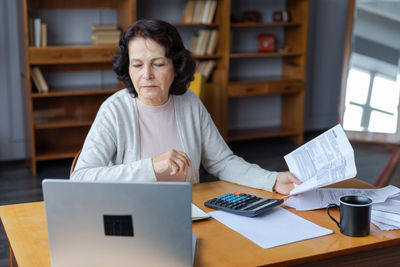 Portrait of woman using laptop while sitting on table