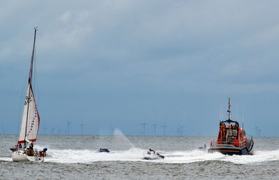 Boats in sea splashing water against sky