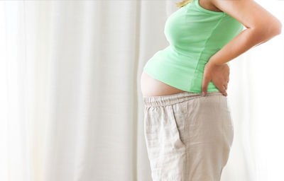 Midsection of woman standing in front of curtain