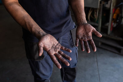 High angle of crop unrecognizable male mechanic showing dirty hands while working in repair service workshop