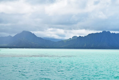 Scenic view of sea and mountains against sky