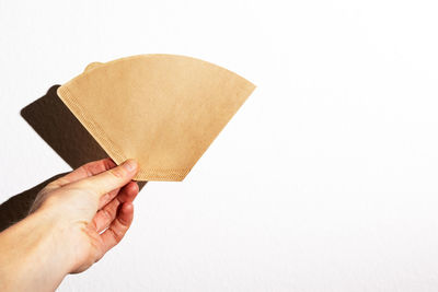 Midsection of person holding paper against white background