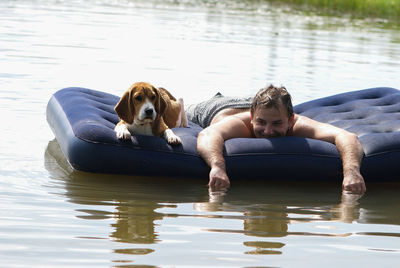 Portrait of mid adult man with dog lying on pool raft