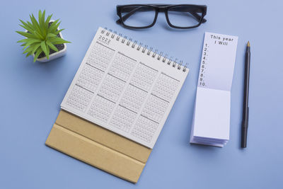 Text on notepad with 2022 calendar, glasses, pen and potted plant on a desk - this year i will