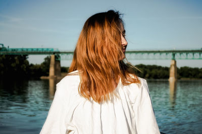 Rear view of woman standing by sea against sky