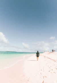 Rear view of man walking at beach against sky