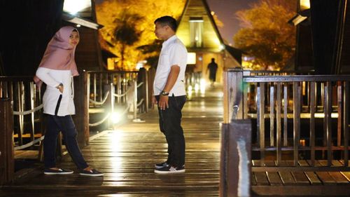 Rear view of young couple standing in illuminated building at night