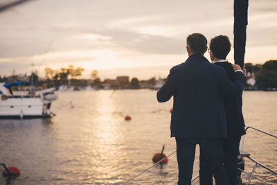 Rear view of senior couple standing on bow of yacht during sunset