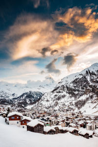 Snow covered houses and mountains against sky