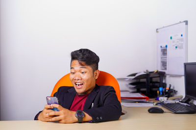 Man using mobile phone while sitting on table