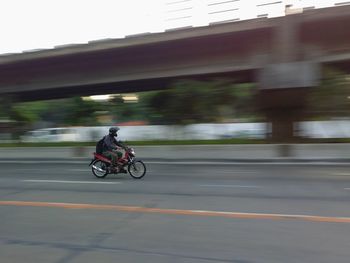 Blurred motion of man riding motorcycle on road