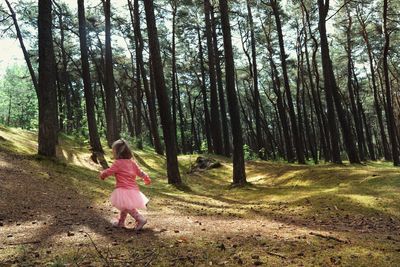 Baby girl walking by trees in forest