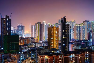 Illuminated modern buildings in city against sky at night