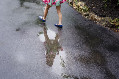 Reflection in a puddle of a smile girl walking down a street in a tutu