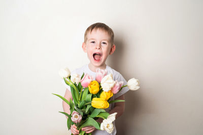 Portrait of cute girl holding bouquet against white background