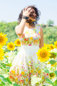 Midsection of woman standing on sunflower field