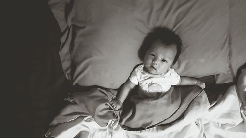 High angle portrait of baby girl lying on bed at home