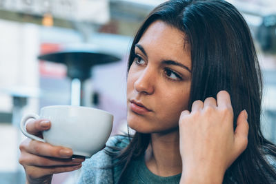 Close-up of thoughtful woman having coffee at sidewalk cafe