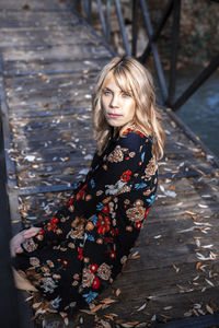 Young woman sitting on a bridge among autumn leaves