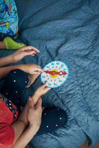 High angle view of people sitting by toy clock on bed