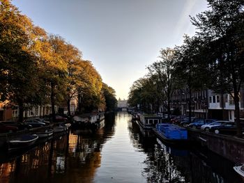 Boats moored in canal against sky in city