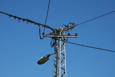 Low angle view of electricity pylon against clear sky