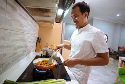 Mid adult man standing in kitchen at home