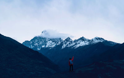 Man standing on snowcapped mountain against sky