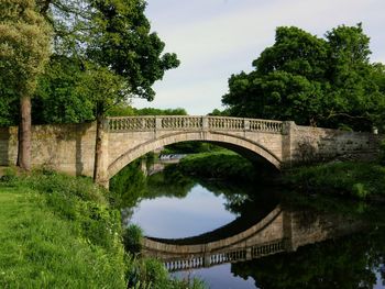 Arch bridge over river against sky