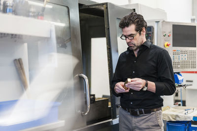 Businessman examining workpiece in a factory