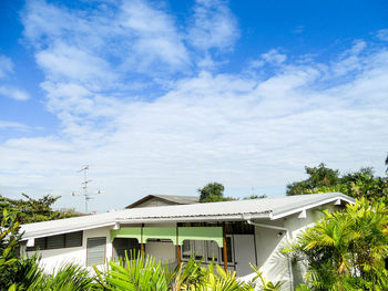 House by palm trees and building against sky