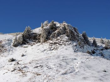 Low angle view of snowcapped mountain against clear blue sky