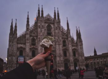 Cropped image of hand holding ice cream cone against duomo di milano