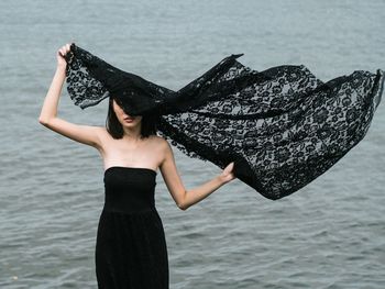 Midsection of woman standing against sea