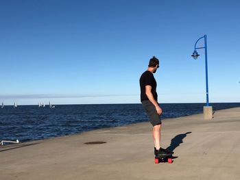 Man skateboarding on pier over sea