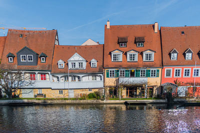 Houses by canal against sky in city